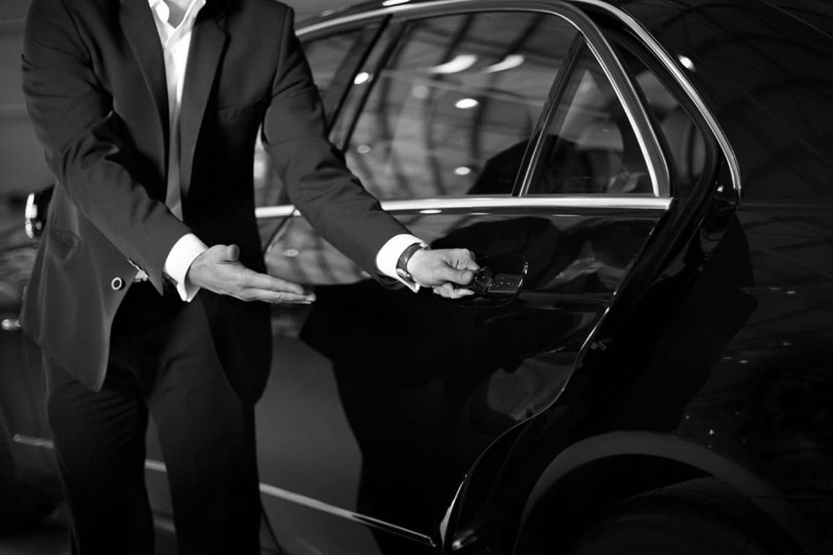 Professional chauffeur in black uniform with 2025 all-black luxury vehicle for private transportation service in Chicago